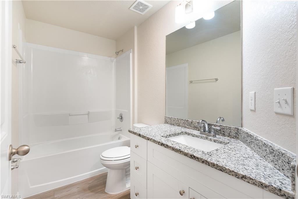 White vanity with chrome hardware, an integrated basin, and a speckled countertop