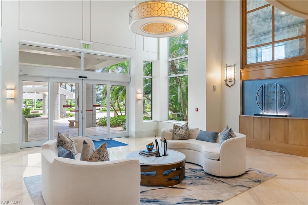 Lobby entrance featuring expansive glass doors, a large drum pendant light fixture, and a recessed wall art installation