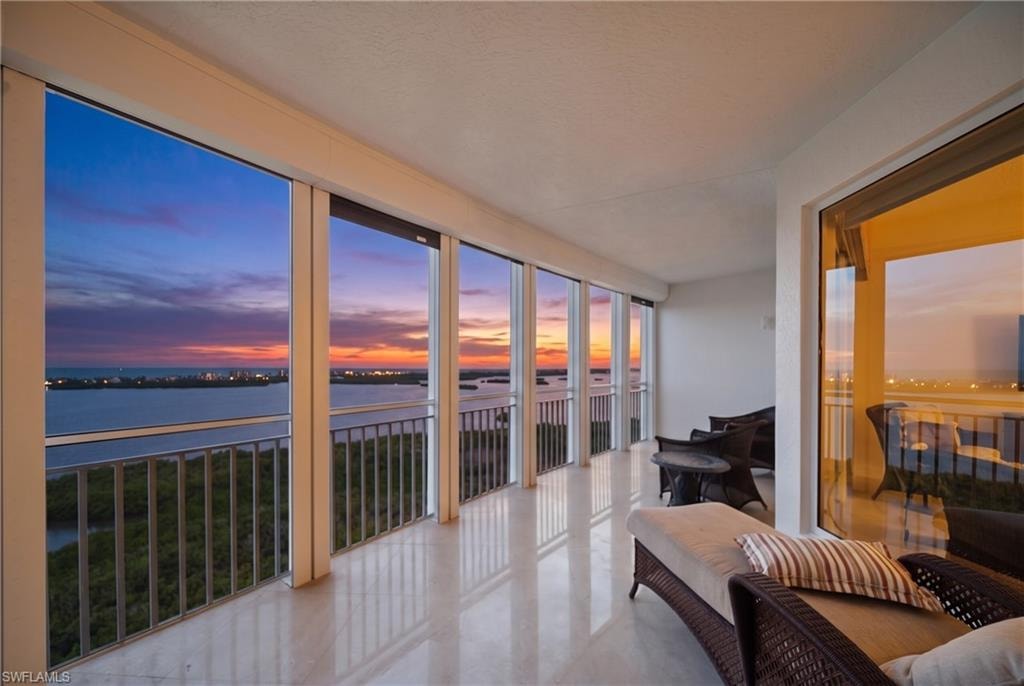 Expansive balcony with floor-to-ceiling windows, reflective flooring, and water scenery