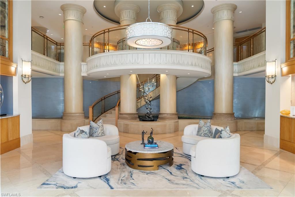 Grand two-story foyer with a curved staircase, decorative columns, and a large circular chandelier