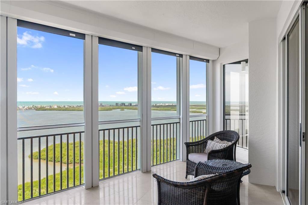 Expansive balcony with floor-to-ceiling windows, white tile flooring, black metal railings, and sliding glass door access