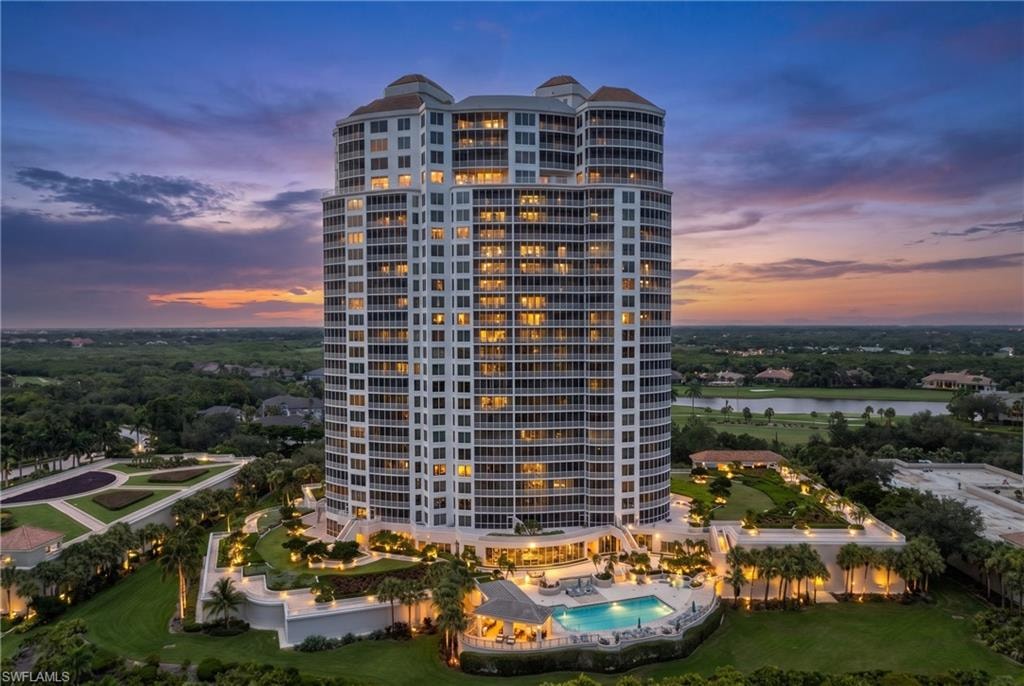 High-rise residential building featuring multiple balconies, a ground-level swimming pool, and a structured landscaping design