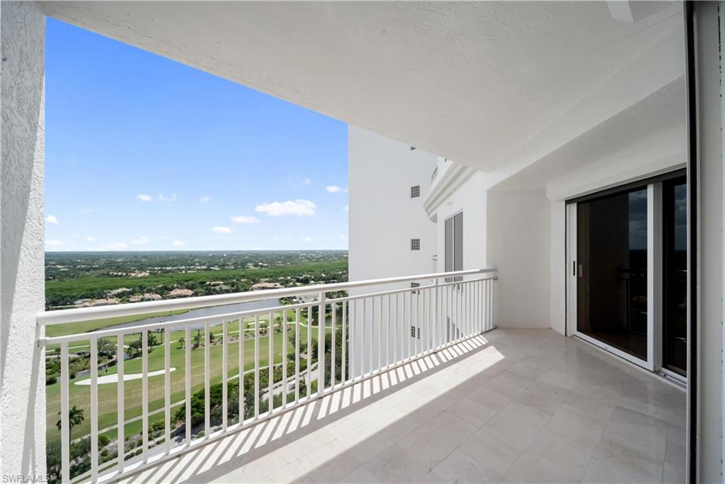 Expansive balcony with tiled flooring, white railing, and sliding glass doors