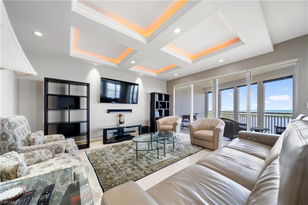 Recessed lighting, tray ceiling with ambient lighting, tile flooring, built-in shelving, and floor-to-ceiling glass doors