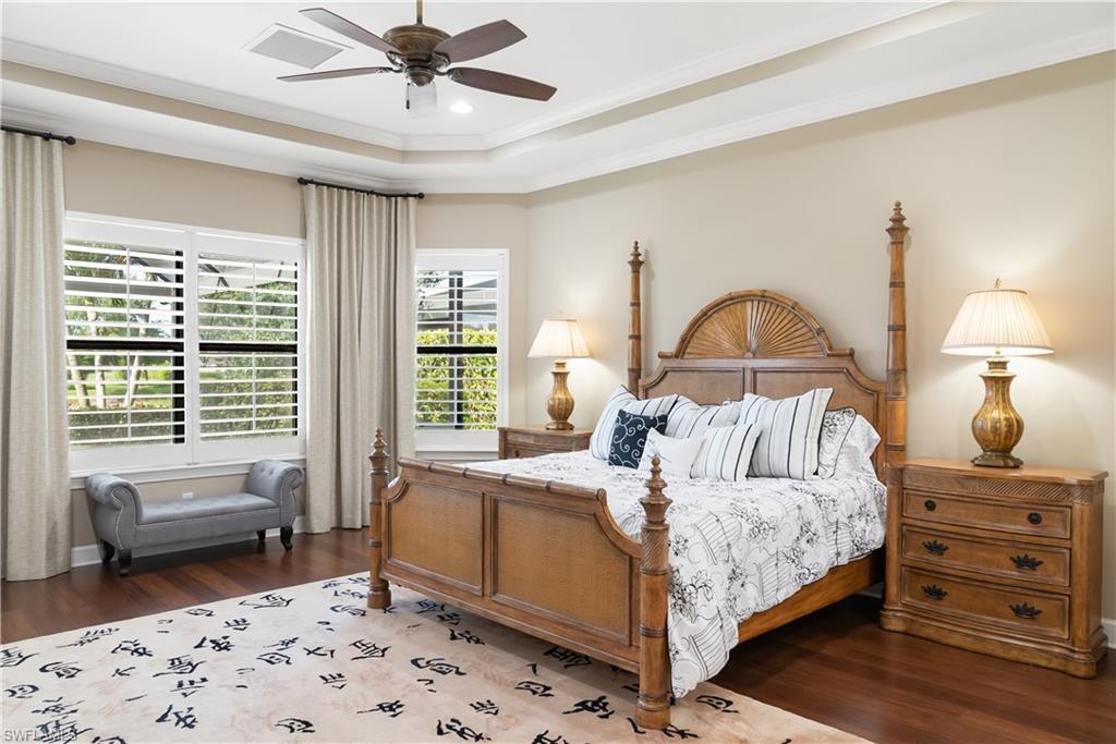 Tray ceiling with a ceiling fan, recessed lighting, wood-finish flooring, and window shutters