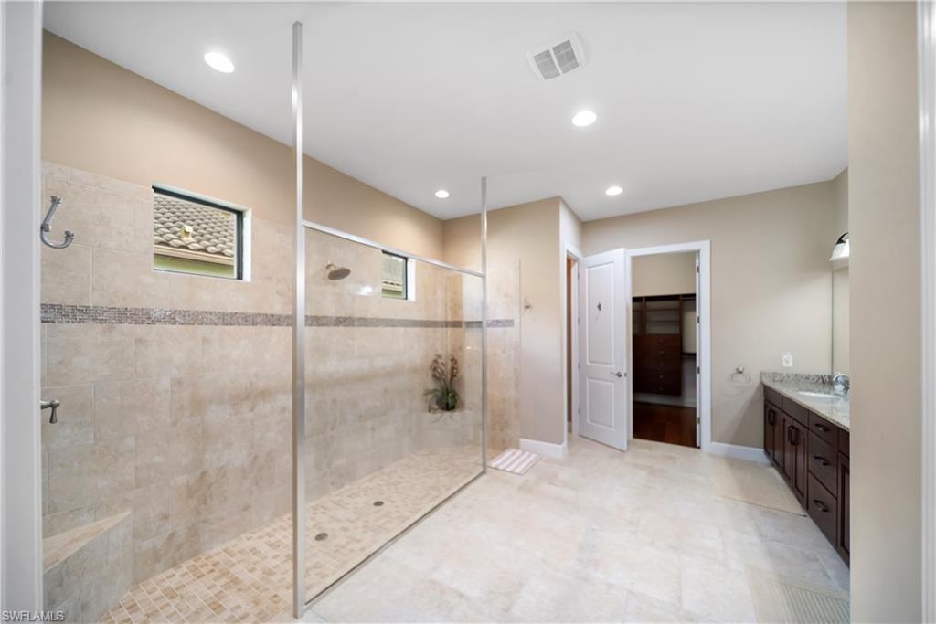 Spacious shower with glass enclosure, tiled walls, and built-in bench
