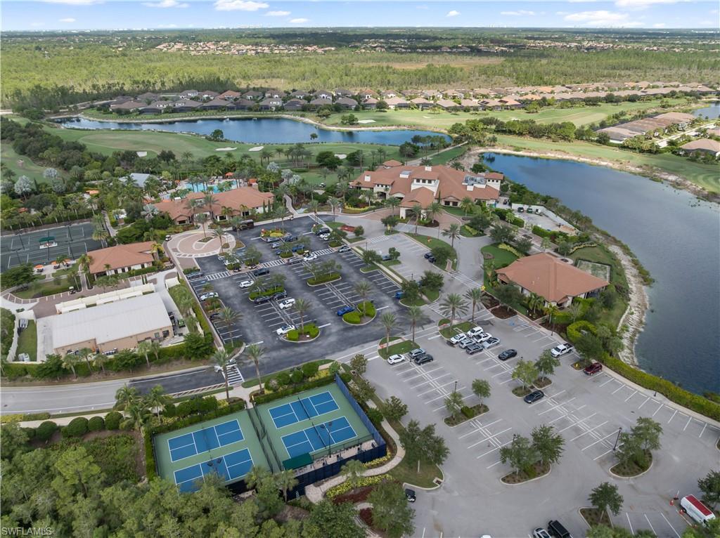 Aerial view featuring a golf course, multiple water features, tennis courts, and several community buildings