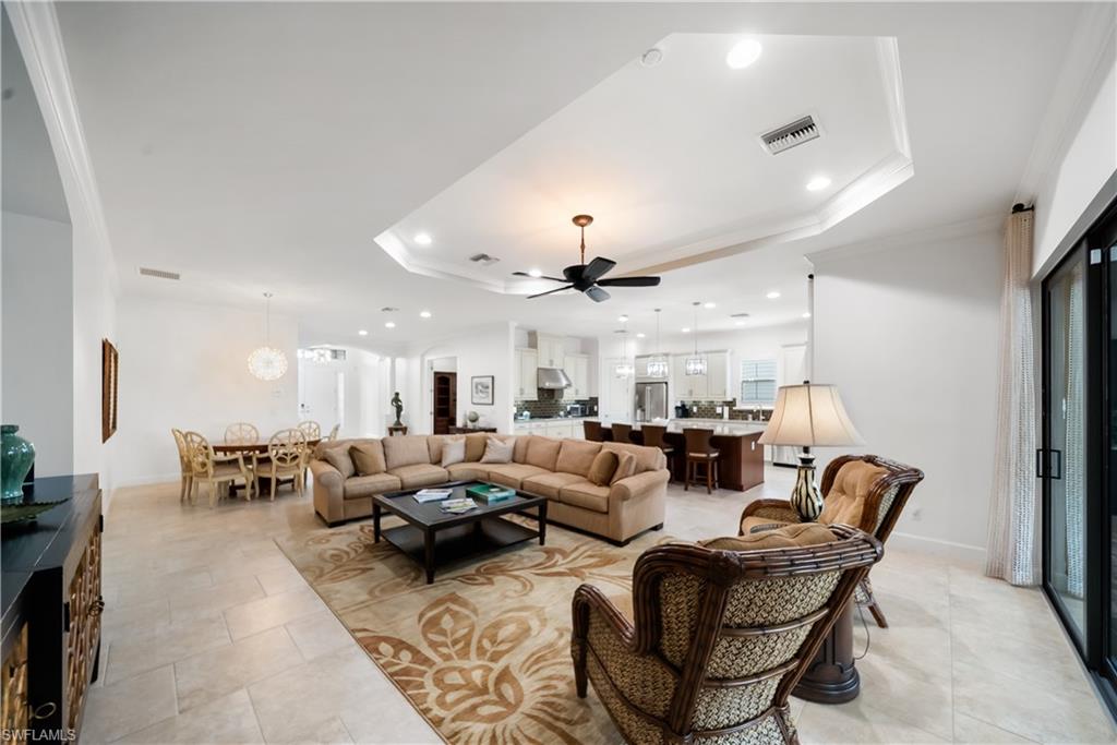 Tray ceiling with recessed lighting, large format tile flooring, sliding glass door, modern ceiling fan, and open-concept design