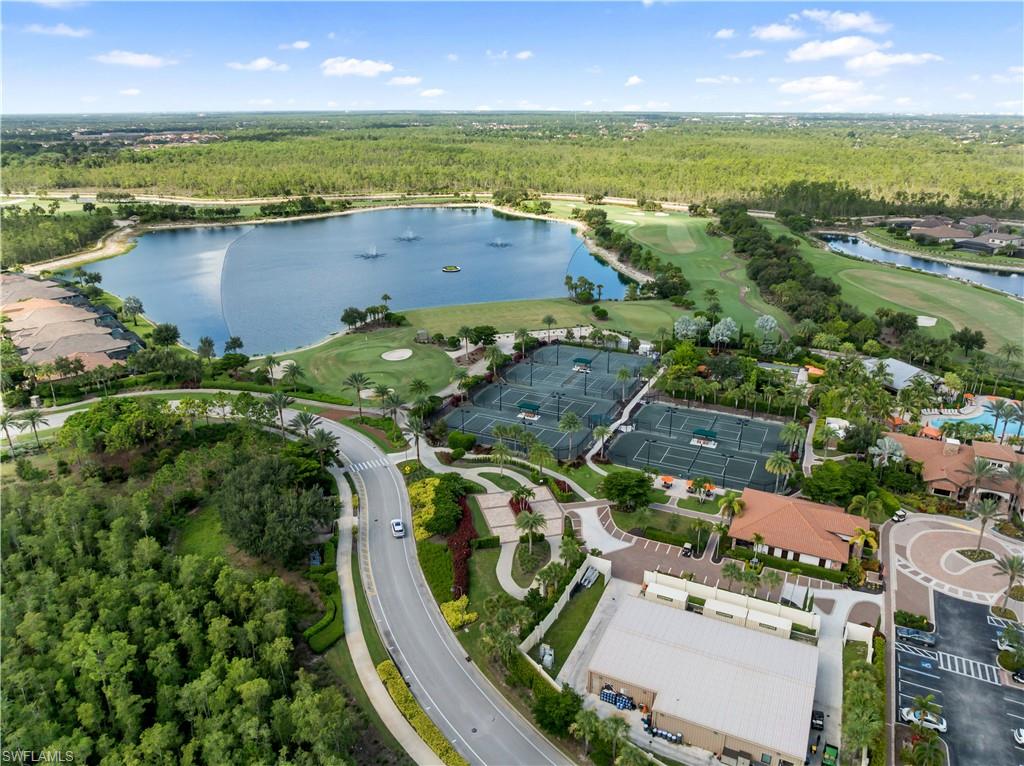 Expansive water feature with multiple fountains, adjacent golf course, multiple tennis courts, and surrounding residential structures