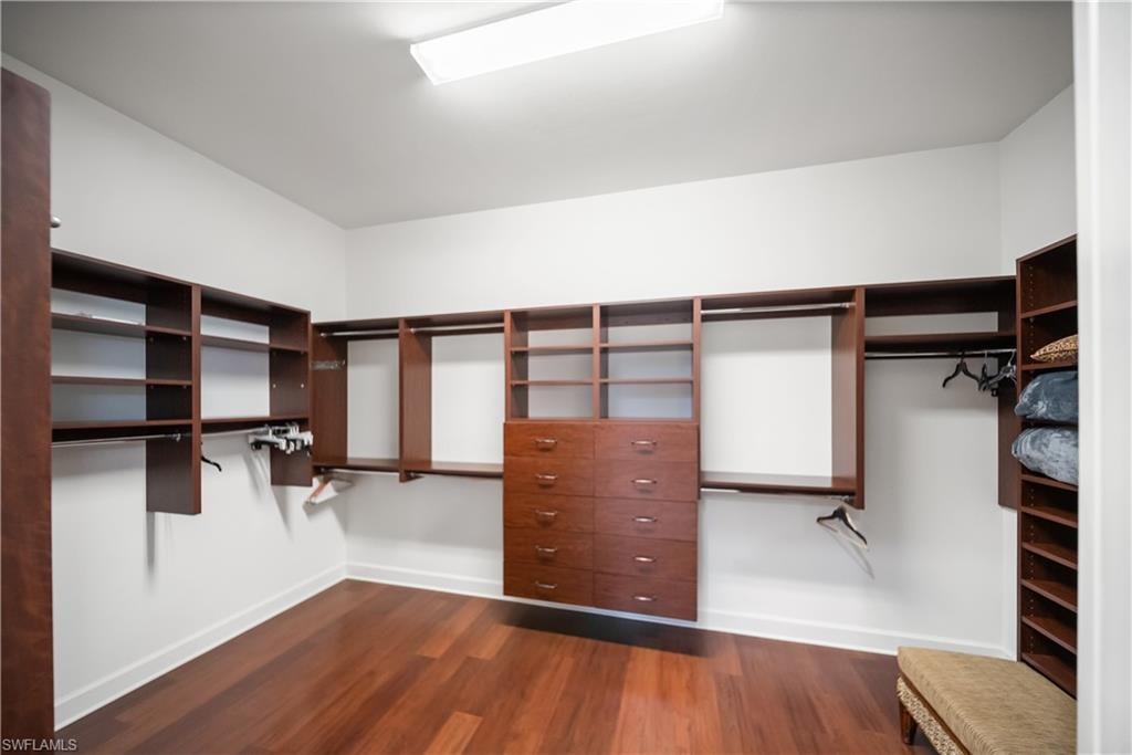 Primary Bedroom Custom built-in closet system with multiple shelving units, hanging rods, and integrated drawers, set against white walls and wood-finish flooring