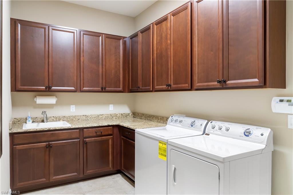 Extensive cabinetry with dark wood-finish doors, L-shaped countertop, integrated sink with chrome faucet, and tile flooring