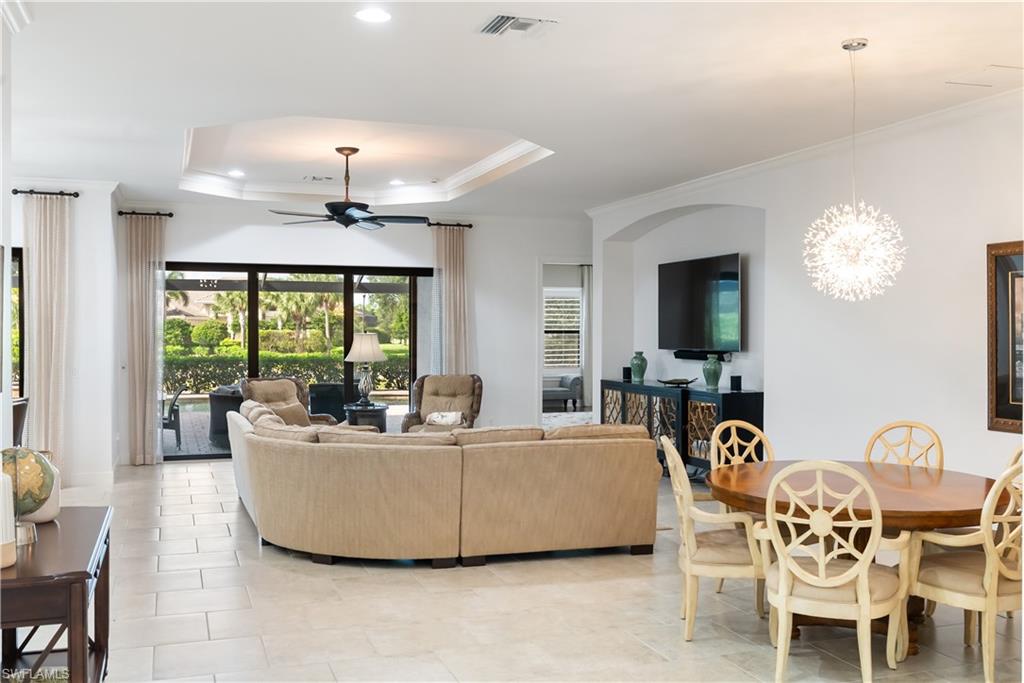 Tiled flooring throughout, tray ceiling with recessed lighting and ceiling fan, sliding glass doors to a covered patio, and a contemporary spherical chandelier