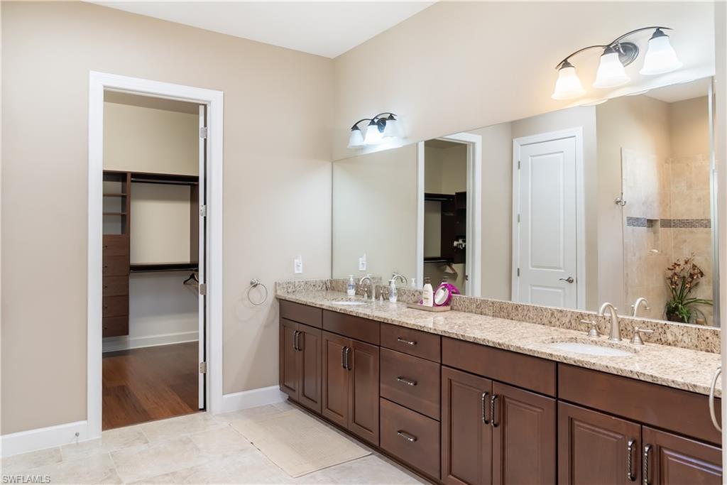 Dual vanity with granite countertop, wood-finish cabinetry, and brushed nickel fixtures