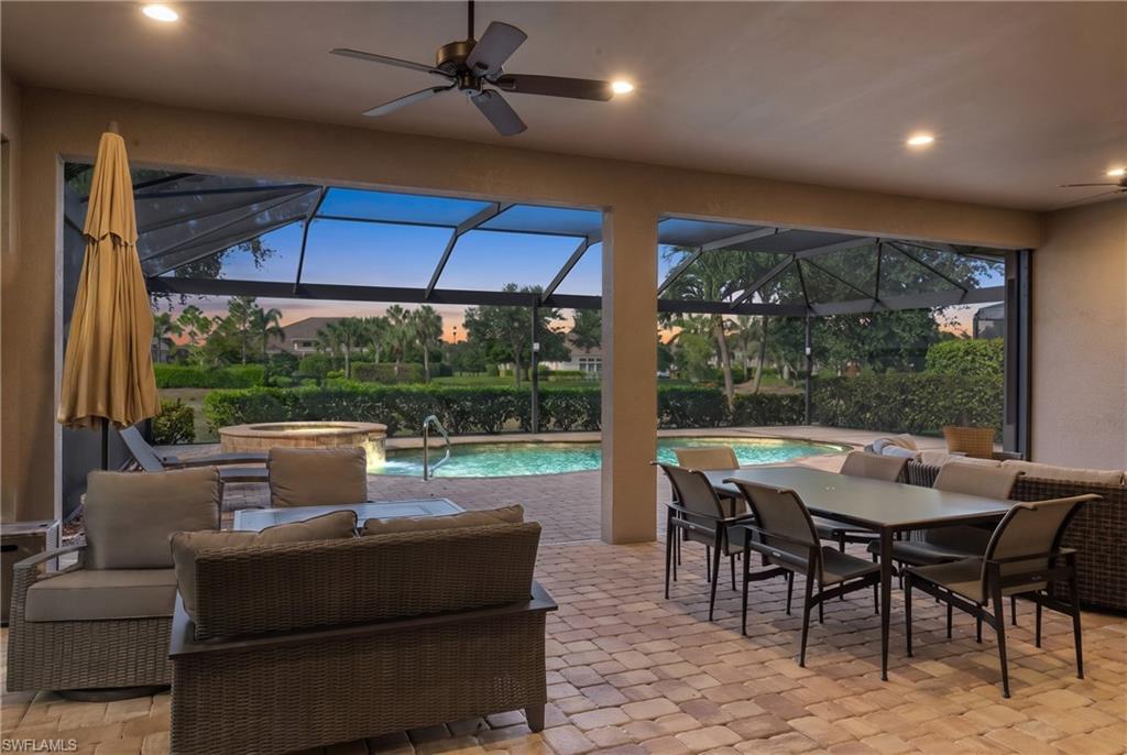 Screened outdoor living area featuring a built-in pool, integrated spa, and paver patio