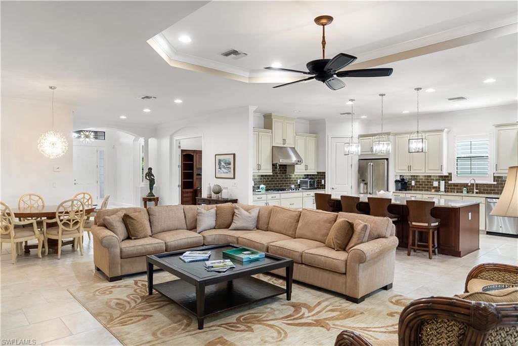 Open-concept living space featuring tray ceilings, recessed lighting, a ceiling fan, and tile flooring