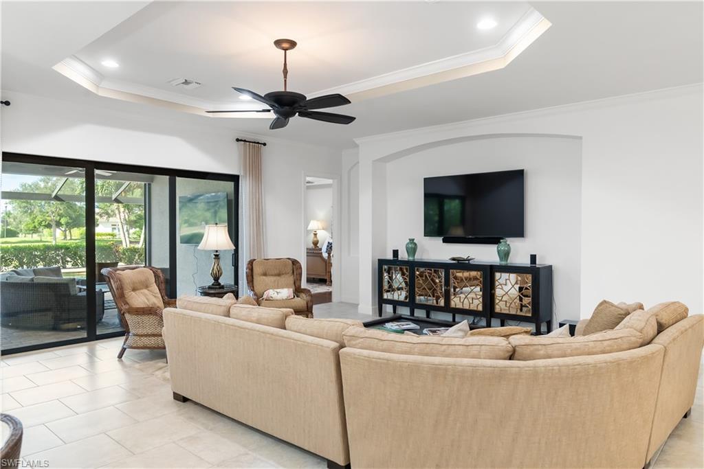 Tray ceiling with recessed lighting and a ceiling fan, large sliding glass doors, arched wall niche, and tile flooring