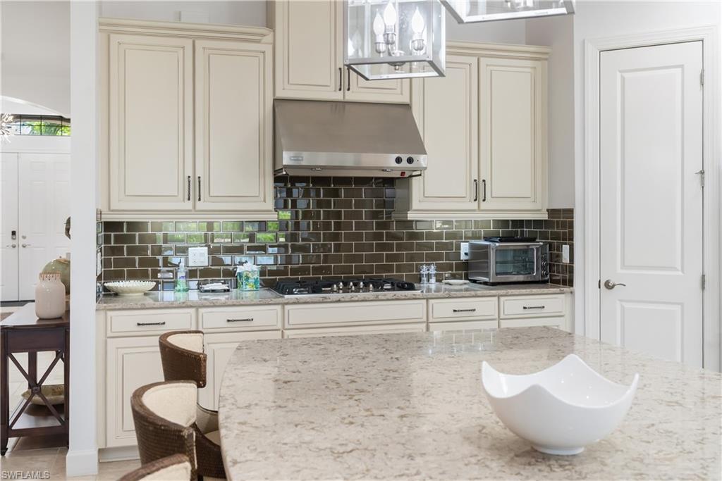 Kitchen featuring cream-colored cabinetry, subway tile backsplash, stainless steel range hood, and a gas cooktop