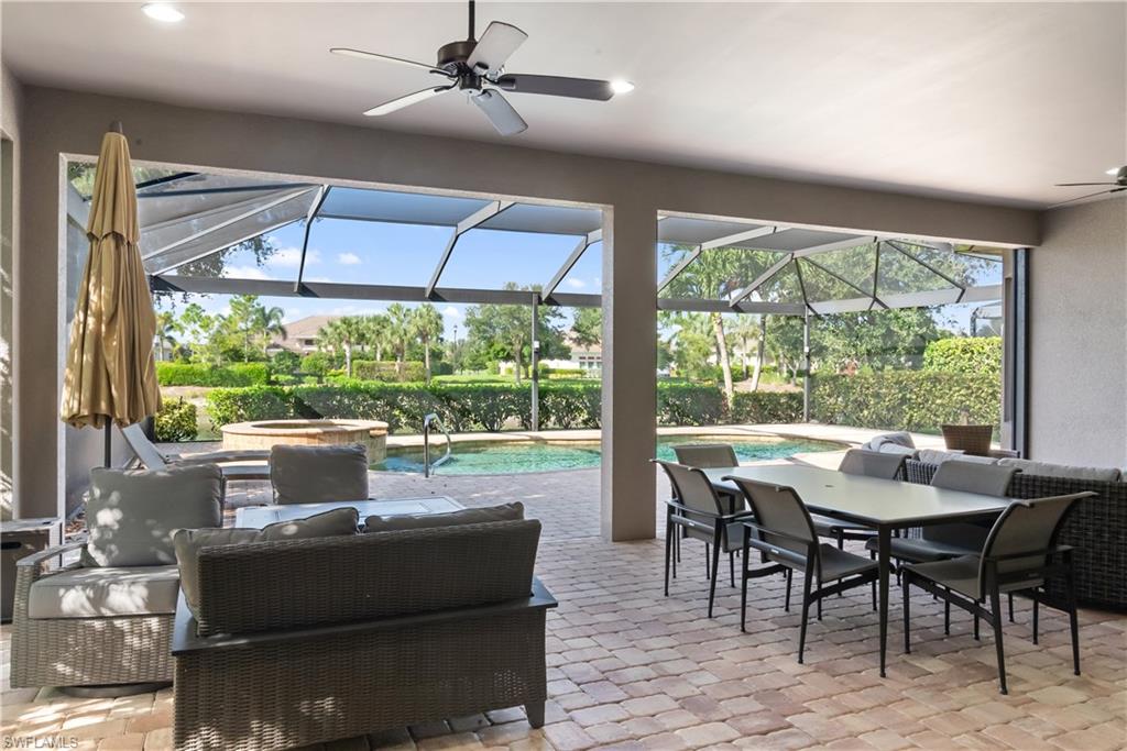 Screened-in paver patio with a swimming pool, integrated spa, and ceiling fans