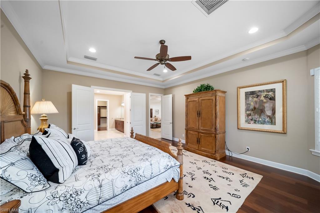 Tray ceiling with crown molding, recessed lighting, ceiling fan, and dark wood-finish flooring