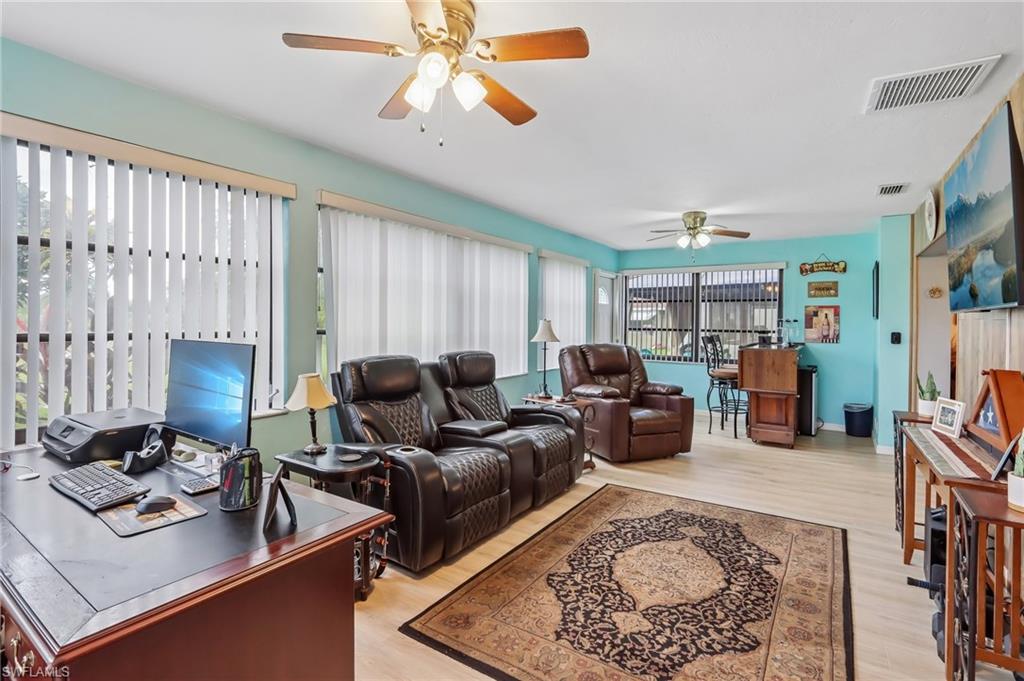 Light wood-finish flooring, multiple ceiling fans, and abundant natural light from numerous windows