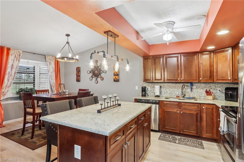 Kitchen featuring wood-finish cabinetry, stainless steel appliances, granite-finish countertops, and a tile backsplash