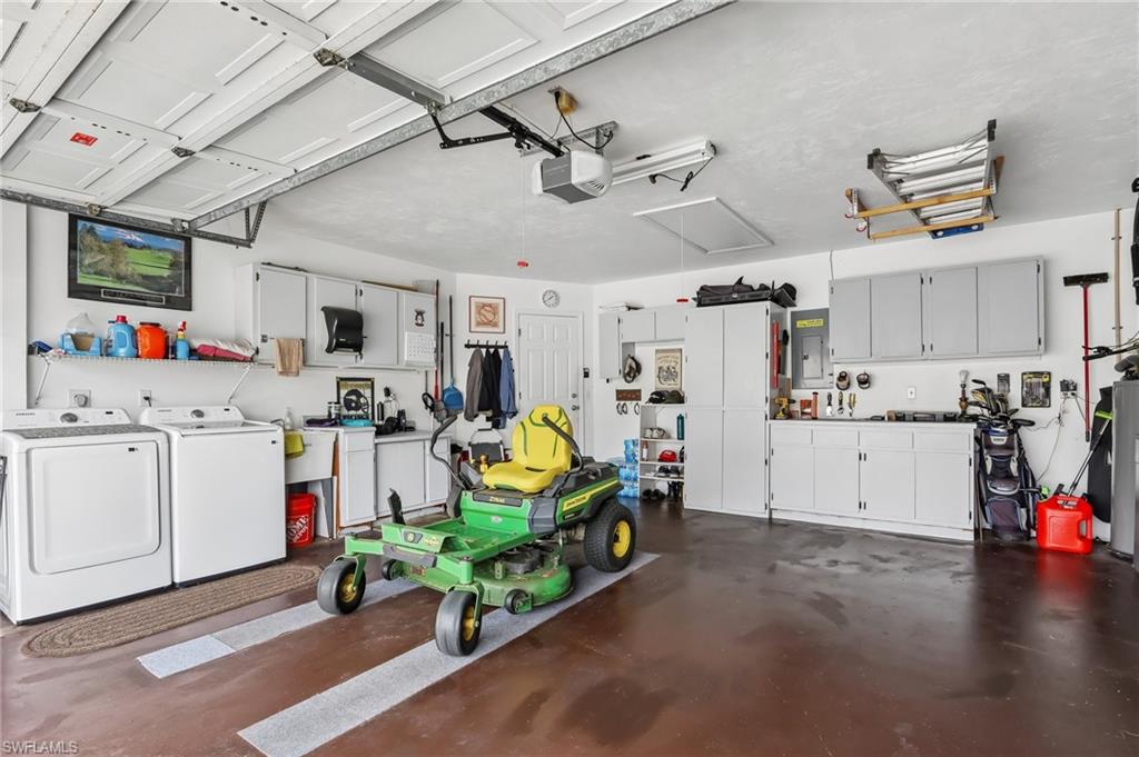 Attached garage with durable flooring, extensive built-in cabinetry, and integrated utility sink