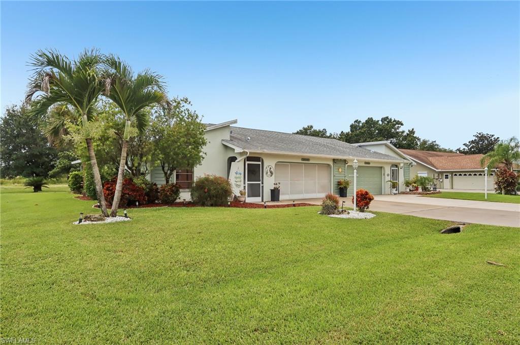 Single-story residence featuring a covered entry, attached garage, and mature landscaping