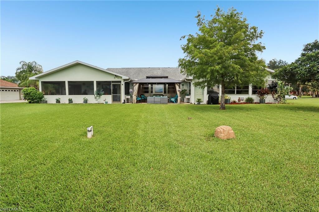 Expansive green space featuring a large screened-in porch, covered outdoor living area, and mature landscaping