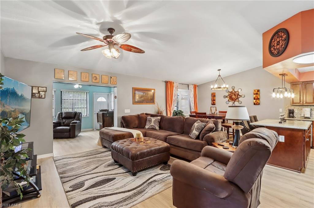 Vaulted ceiling with a ceiling fan, light wood-finish flooring, recessed lighting, and a kitchen island with stone countertop
