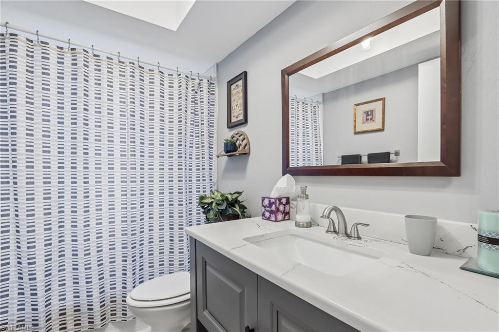 Vanity with a white countertop and integrated sink, brushed nickel faucet, and a large framed mirror