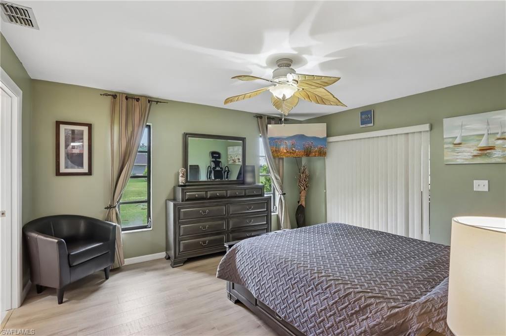 Light wood-finish flooring with a ceiling fan featuring palm leaf-style blades