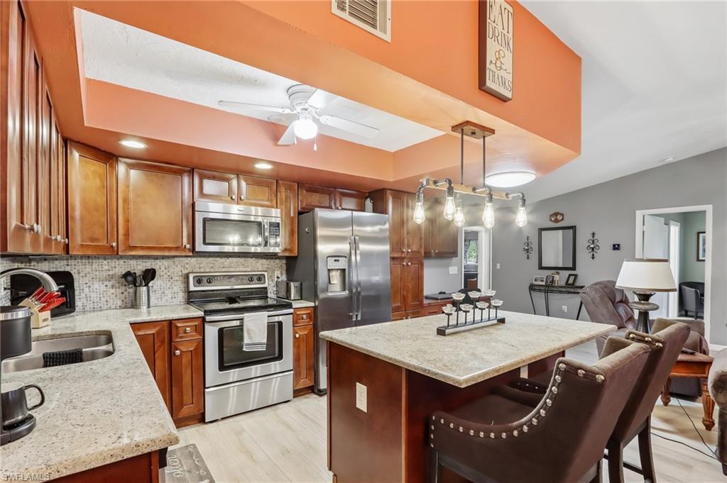 Kitchen featuring wood-finish cabinetry, stainless steel appliances, and a central island with countertop seating