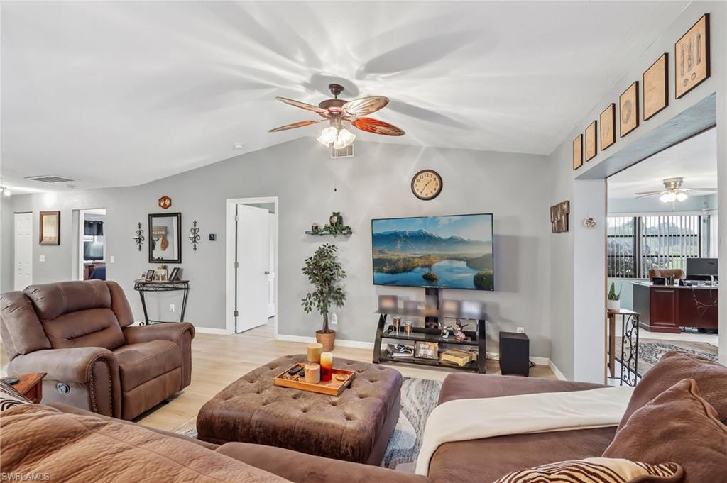 Vaulted ceiling, wood-finish flooring, ceiling fan with integrated lighting, recessed lighting, and an arched doorway