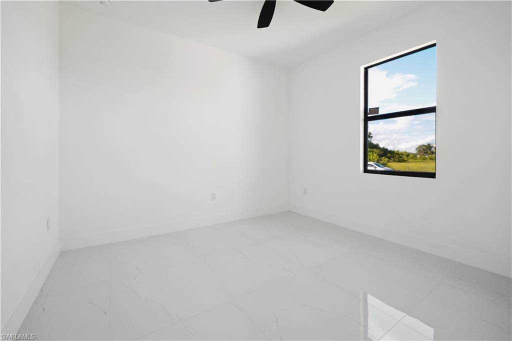 Clean white walls with a black ceiling fan, paired with large format light-toned floor tiles