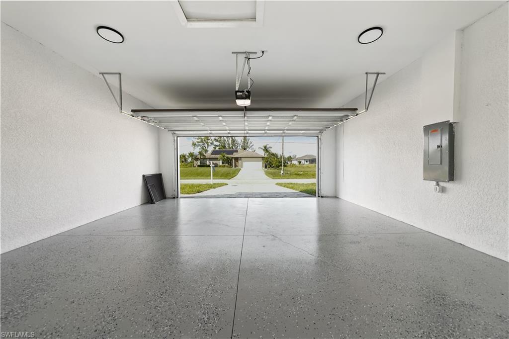Spacious garage with an epoxy-coated concrete floor, overhead lighting, and a clear overhead door