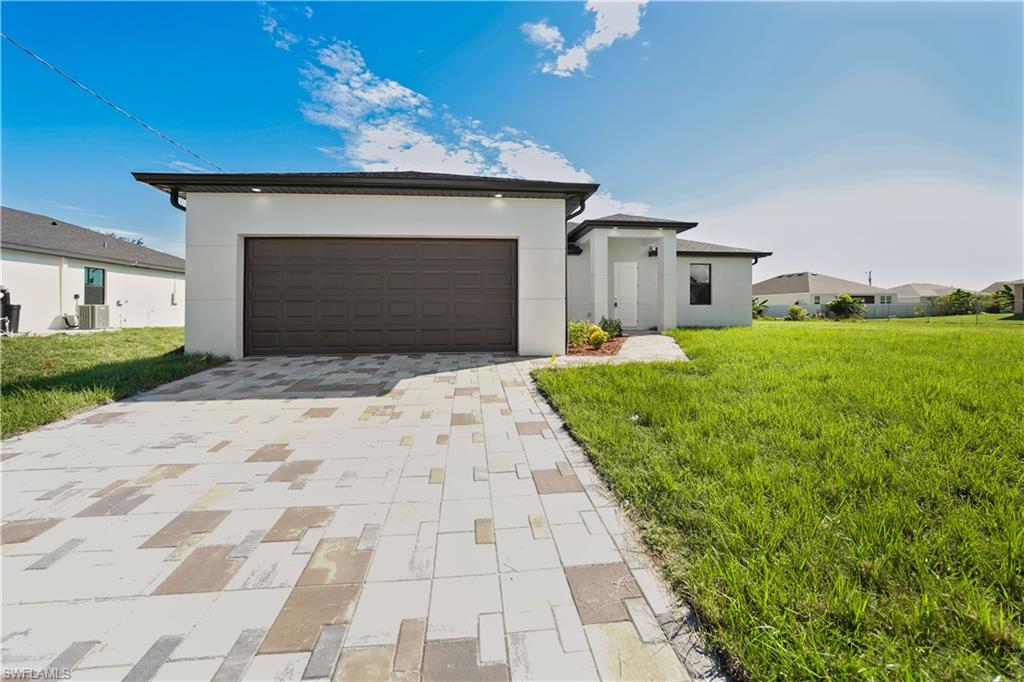 Contemporary exterior with a dark garage door, white stucco siding, and a paver driveway