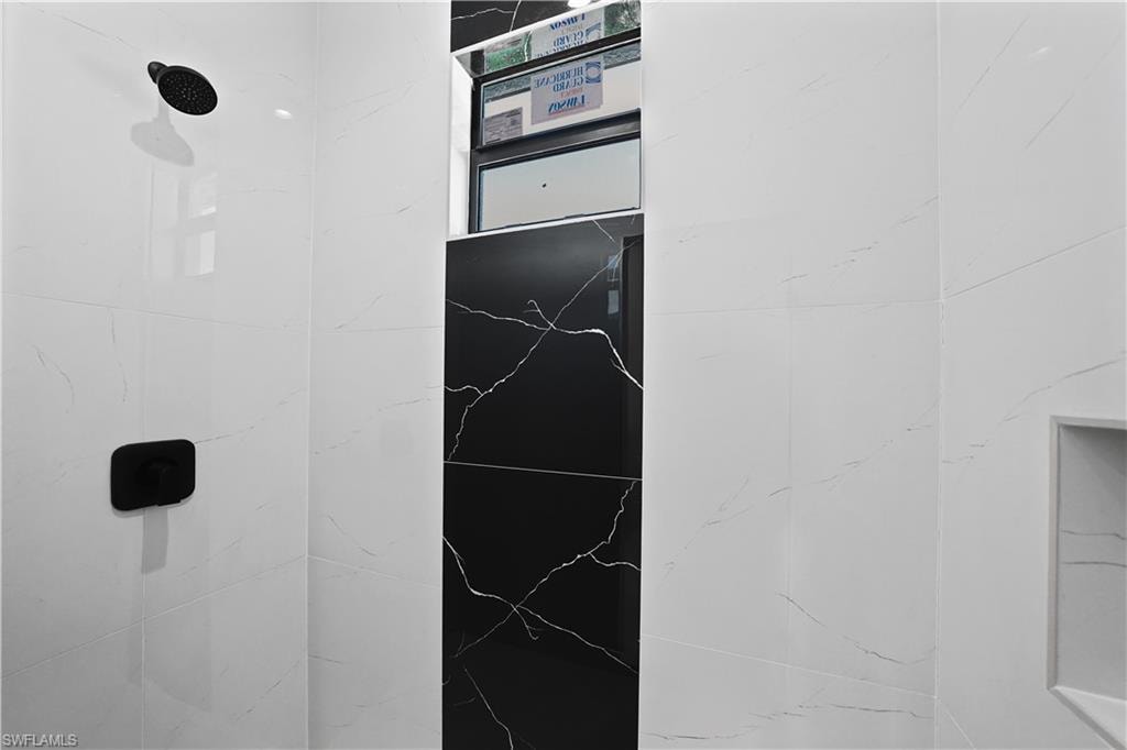 Black and white tiled shower with a niche and matte black fixtures