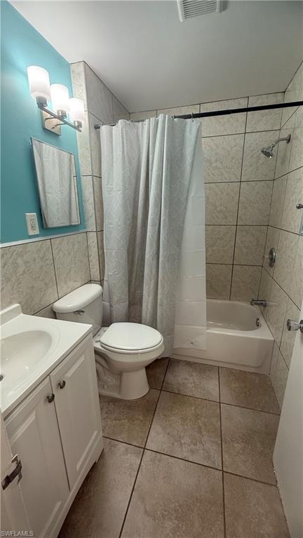 Full bath with shower / bath combo, vanity, tile walls, and light tile patterned flooring