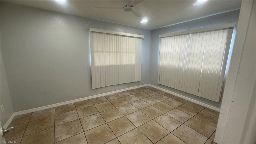 Tiled empty room featuring baseboards and ceiling fan