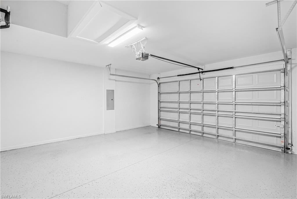 Garage with an overhead door, finished walls, overhead lighting, and an epoxy-coated concrete floor