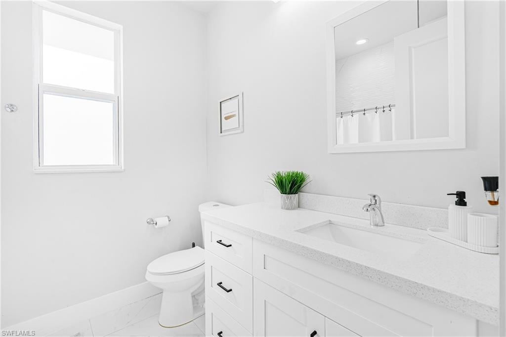 White vanity with a light-toned countertop, integrated sink, and chrome faucet
