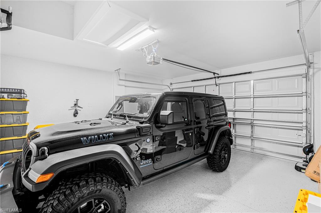 Attached garage featuring a light-colored epoxy floor and overhead fluorescent lighting
