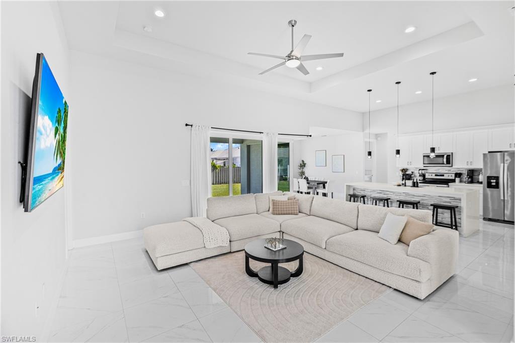 Spacious open-concept living area featuring high vaulted ceilings, large format tile flooring, and sliding glass doors to the exterior