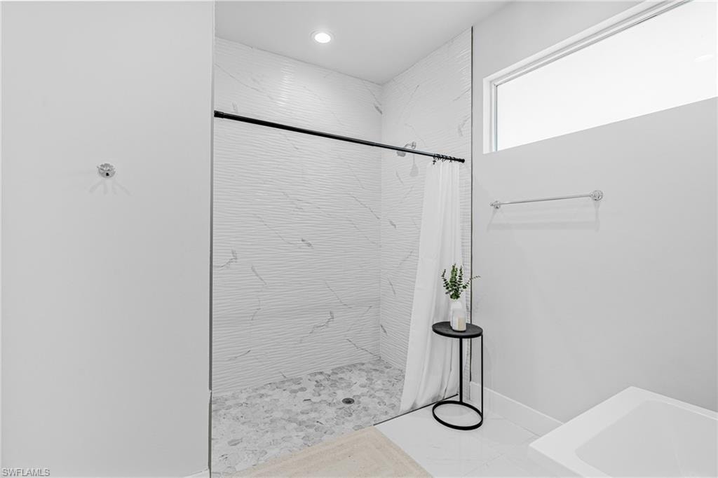 Walk-in shower with clear glass enclosure and stone tile flooring
