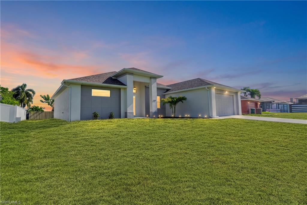 Modern exterior with a light-toned stucco finish, prominent front entryway, an attached garage, and a spacious front lawn