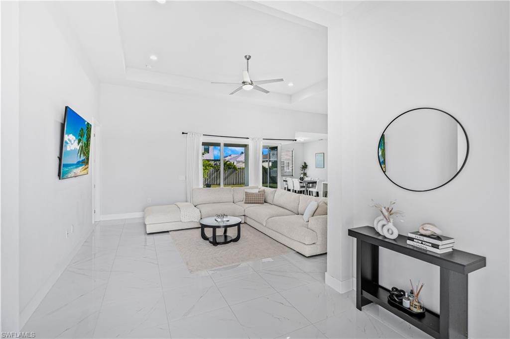 Spacious living area featuring white tile flooring, vaulted ceilings, and recessed lighting