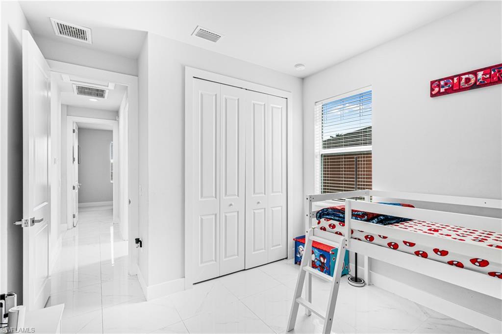 White tile flooring, white walls, white bi-fold closet doors, white trim, and a window with blinds