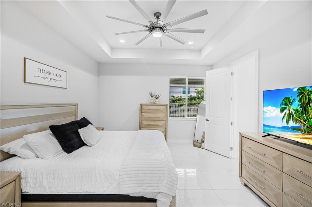 Tray ceiling with recessed lighting and a ceiling fan, white wall paint, white tile flooring, and a white interior door
