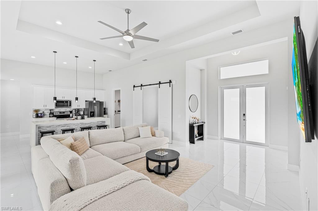 Spacious open-concept living area featuring high ceilings, recessed lighting, and large format polished tile flooring