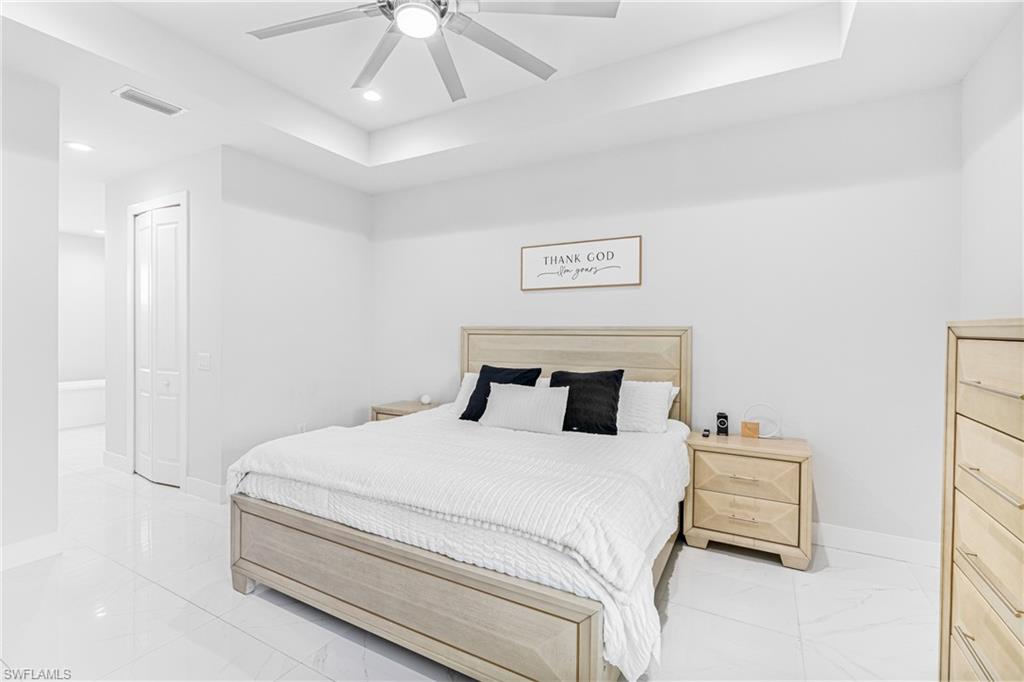 Recessed lighting, ceiling fan, tray ceiling, tile flooring, and bi-fold closet doors